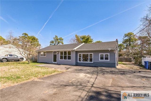 ranch-style house with a chimney, a front yard, and fence