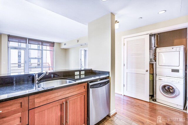 20 Livingston Ave Unit 902, New Brunswick, NJ 08901 - kitchen with dishwasher, stacked washing machine and dryer, brown cabinetry, light wood-style floors, and dark stone counters