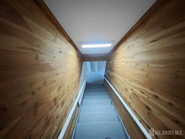 hallway with wood walls and lofted ceiling with skylight