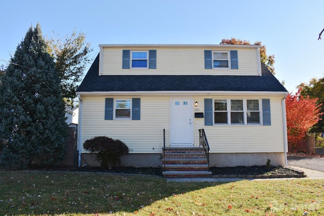 bungalow-style house with entry steps, roof with shingles, and a front yard