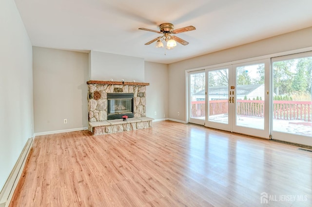 unfurnished living room featuring baseboard heating, light hardwood / wood-style flooring, ceiling fan, french doors, and a fireplace