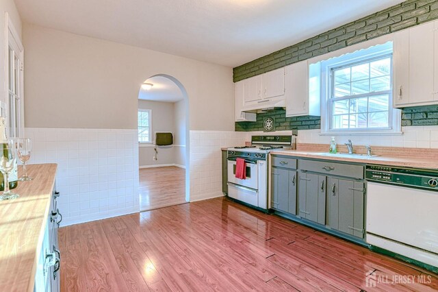 kitchen with sink, white cabinetry, white appliances, and light hardwood / wood-style flooring