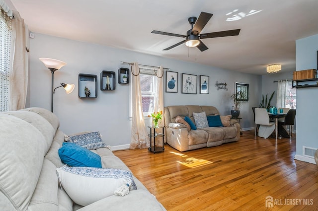living area featuring light wood-style floors, baseboards, ceiling fan, and visible vents