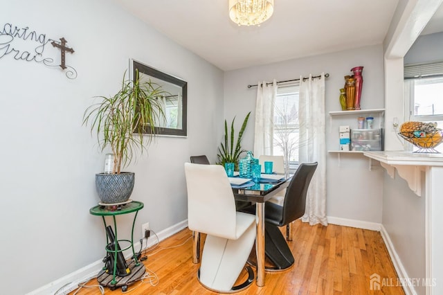 dining area with light wood-style floors, baseboards, and an inviting chandelier