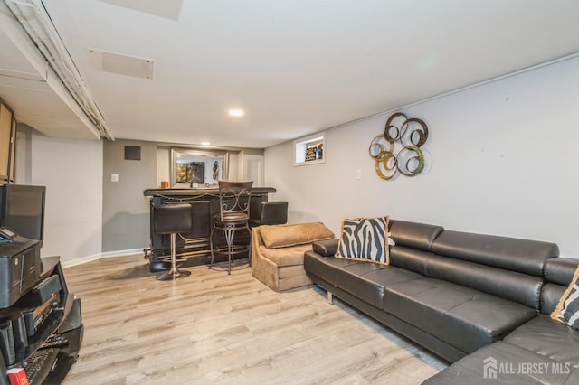 living area featuring a bar, baseboards, and wood finished floors