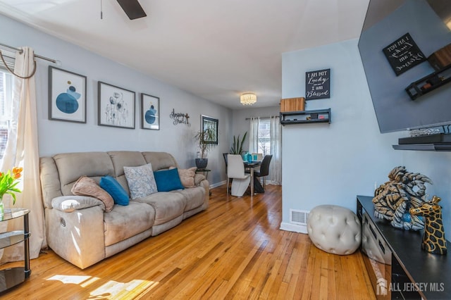 living room featuring a ceiling fan, baseboards, visible vents, and hardwood / wood-style flooring