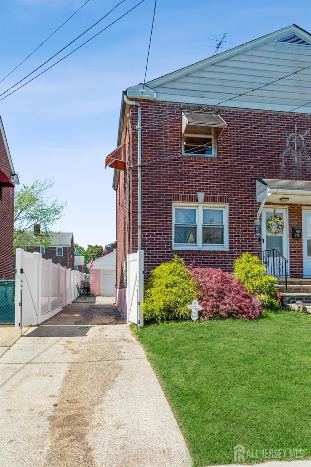 view of front of house featuring brick siding, fence, a front yard, and concrete driveway