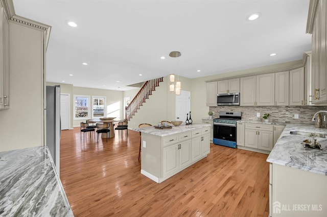 176 Easy St, Edison, NJ 08817 - kitchen featuring appliances with stainless steel finishes, a sink, light wood-style floors, tasteful backsplash, and a center island