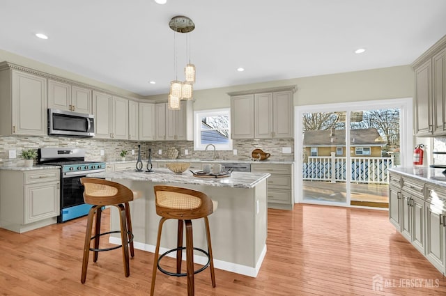 176 Easy St, Edison, NJ 08817 - kitchen with stainless steel appliances, a breakfast bar area, decorative backsplash, light wood-style floors, and a kitchen island