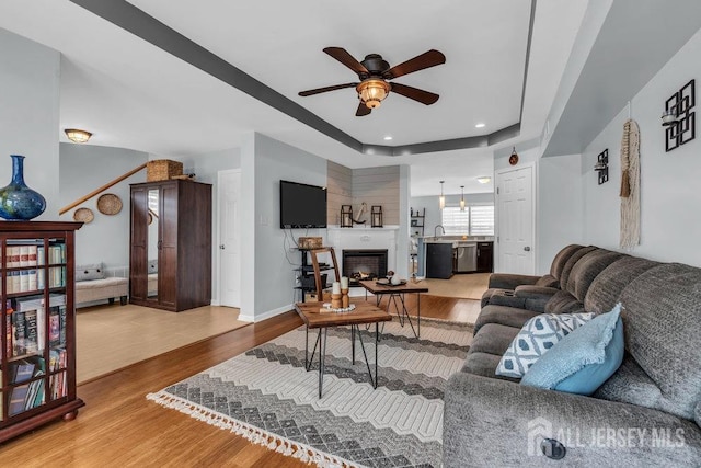 904 4th St, Union Beach, NJ 07735 - living room with a lit fireplace, a raised ceiling, a ceiling fan, and wood finished floors