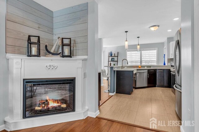 904 4th St, Union Beach, NJ 07735 - kitchen featuring a peninsula, dishwasher, light countertops, a lit fireplace, and hanging light fixtures