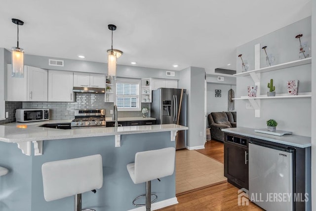 904 4th St, Union Beach, NJ 07735 - kitchen with a peninsula, stainless steel appliances, open shelves, visible vents, and under cabinet range hood