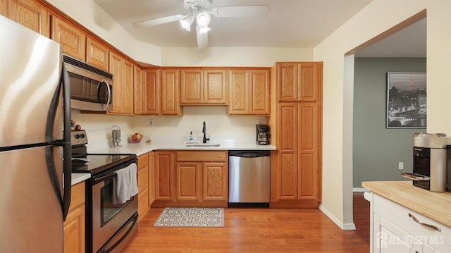 kitchen with ceiling fan, appliances with stainless steel finishes, sink, and light hardwood / wood-style flooring