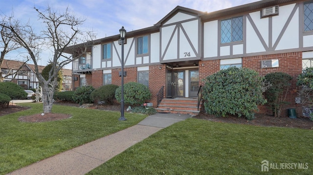 tudor-style house featuring brick siding, a front yard, and stucco siding