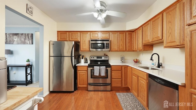 kitchen featuring sink, light hardwood / wood-style floors, ceiling fan, and appliances with stainless steel finishes