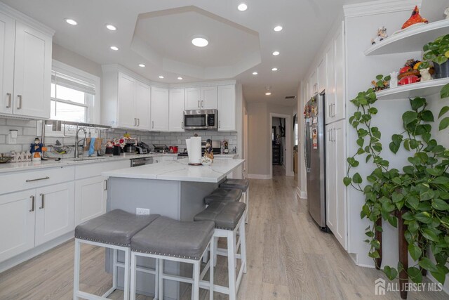 118 Holly St, Port Reading, NJ 07064 - kitchen featuring stainless steel appliances, a sink, decorative backsplash, white cabinets, and light wood-style flooring