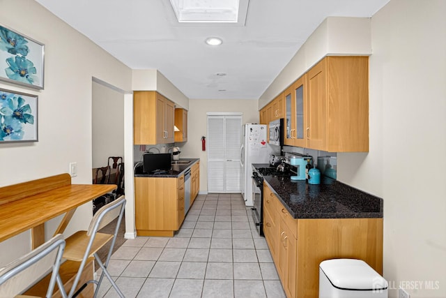 29 Whittney Ct, East Brunswick, NJ 08816 - kitchen featuring range with gas stovetop, stainless steel microwave, glass insert cabinets, light tile patterned flooring, and dark stone counters