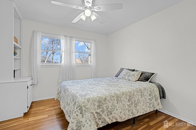 bedroom with a ceiling fan, baseboards, and wood finished floors