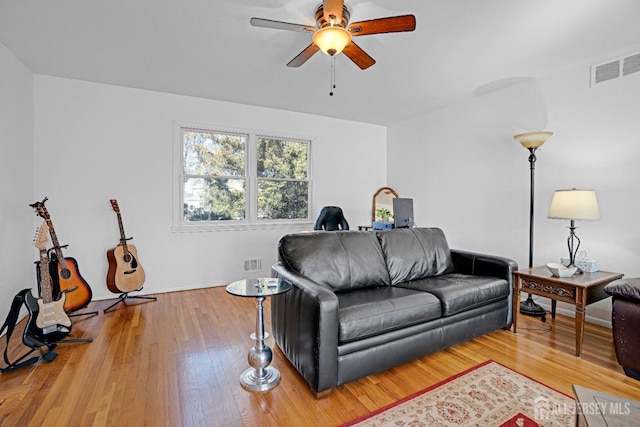 living room with wood-type flooring, visible vents, and a ceiling fan