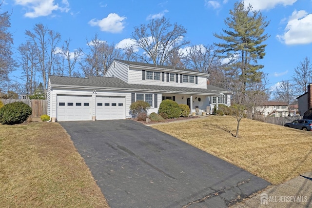 traditional-style home with aphalt driveway, a front yard, fence, and a garage