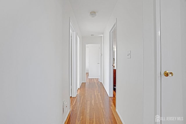 hall with light wood-style flooring and baseboards