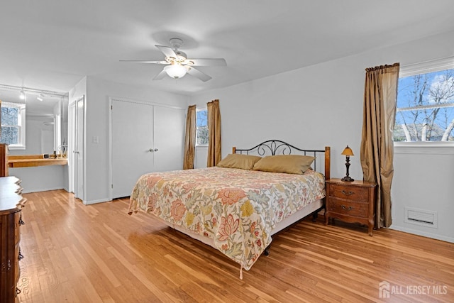 bedroom featuring light wood-type flooring, multiple windows, visible vents, and a closet