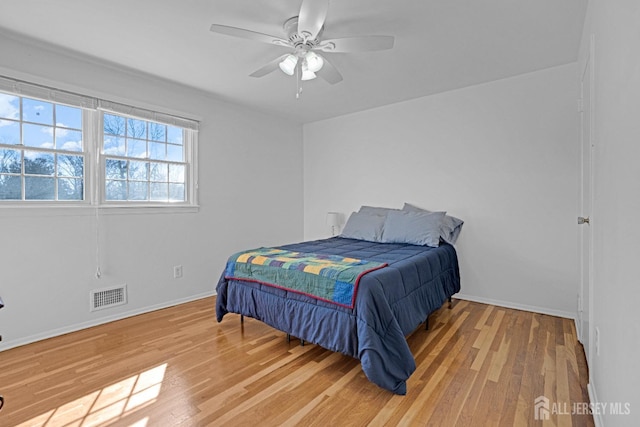 bedroom featuring ceiling fan, wood finished floors, visible vents, and baseboards