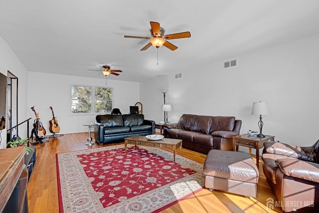 living area featuring a ceiling fan, visible vents, and wood finished floors