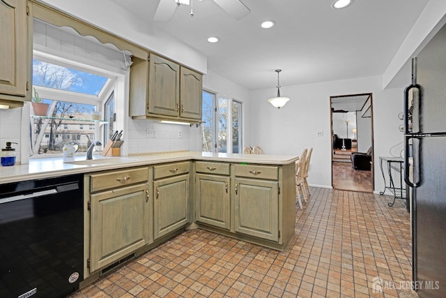 kitchen featuring decorative backsplash, a peninsula, light countertops, black appliances, and a sink