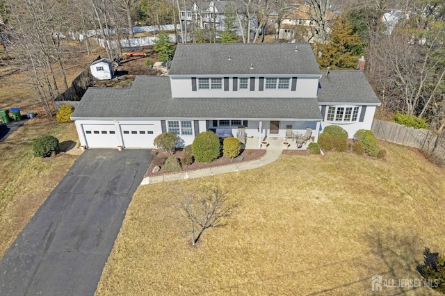 view of front facade featuring a garage, aphalt driveway, a front lawn, and fence