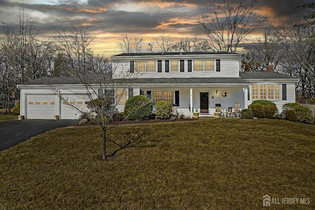 traditional-style home featuring covered porch, a yard, and aphalt driveway