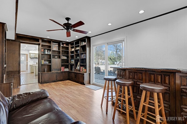 living area with built in shelves, a dry bar, recessed lighting, light wood-style flooring, and ceiling fan