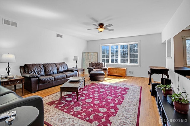 living room with a ceiling fan, visible vents, and wood finished floors