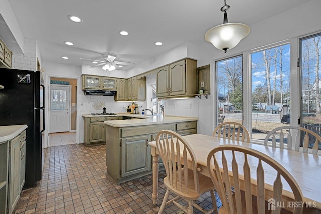 kitchen featuring recessed lighting, a peninsula, light countertops, backsplash, and freestanding refrigerator