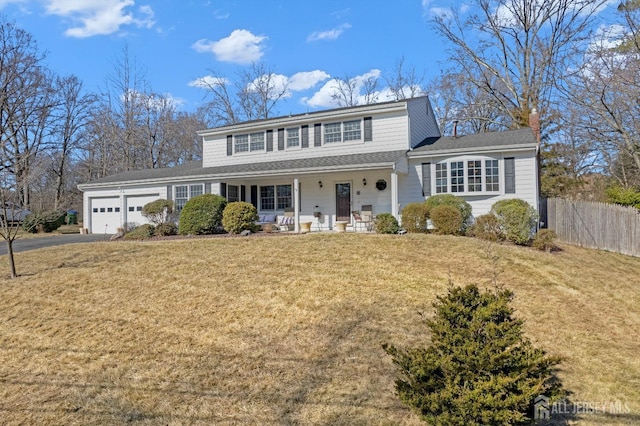 view of front facade featuring an attached garage, a porch, fence, and a front lawn