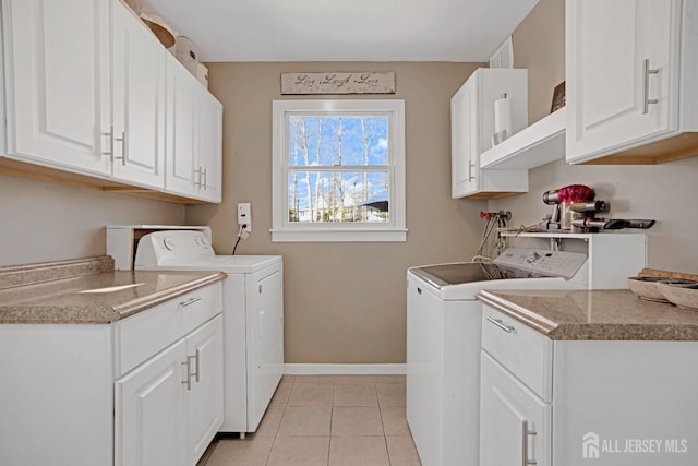 washroom with light tile patterned floors, separate washer and dryer, cabinet space, and baseboards