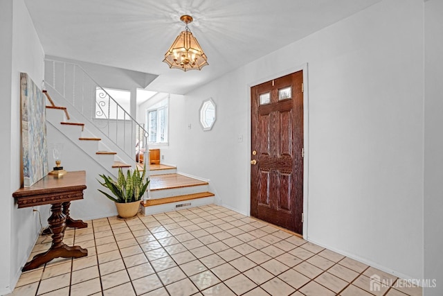 entryway with an inviting chandelier, visible vents, stairway, and light tile patterned flooring