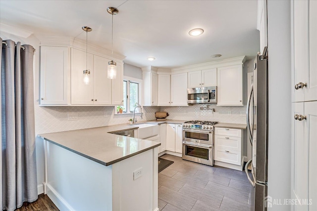 24 Turner Ct, Metuchen, NJ 08840 - kitchen with stainless steel appliances, a peninsula, backsplash, white cabinetry, and pendant lighting