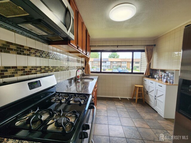 74 Probasco Rd, East Windsor, NJ 08520 - kitchen with appliances with stainless steel finishes, tile walls, a textured ceiling, stone tile floors, and brown cabinetry