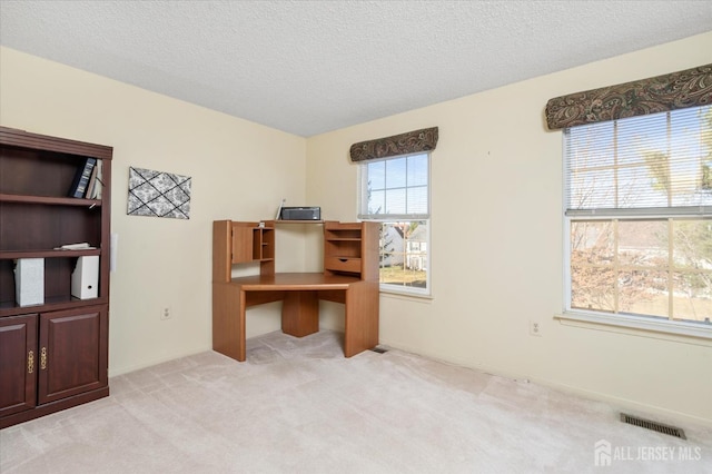 home office with light colored carpet, visible vents, and a textured ceiling