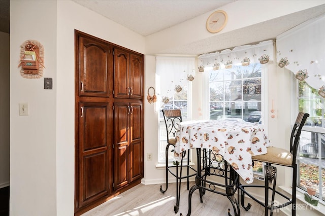 dining space featuring light wood-style floors and a textured ceiling