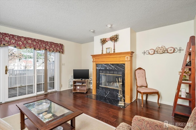living room featuring baseboards, wood finished floors, a high end fireplace, and a textured ceiling