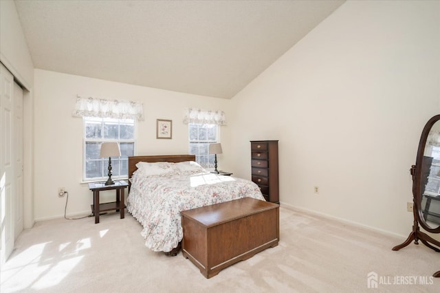 bedroom with light colored carpet, baseboards, high vaulted ceiling, and a closet