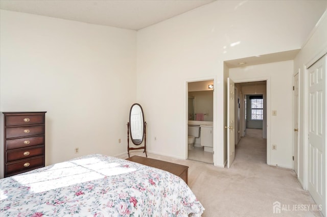 bedroom featuring a closet, ensuite bath, light carpet, and baseboards