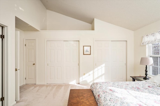 carpeted bedroom featuring two closets and lofted ceiling