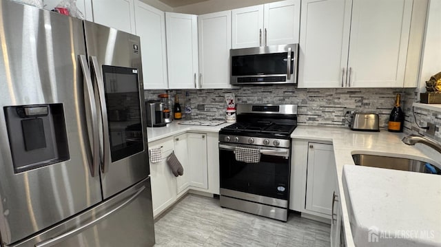 kitchen featuring a sink, stainless steel appliances, tasteful backsplash, and white cabinets