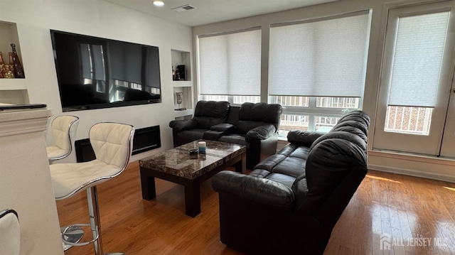 living room featuring recessed lighting, visible vents, built in features, and wood finished floors