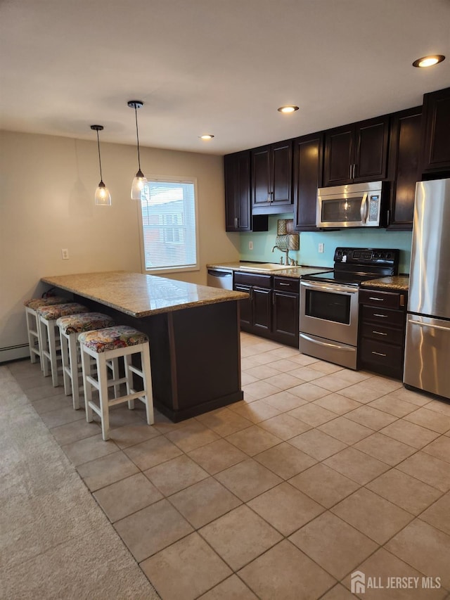 kitchen with recessed lighting, a sink, a kitchen breakfast bar, appliances with stainless steel finishes, and pendant lighting