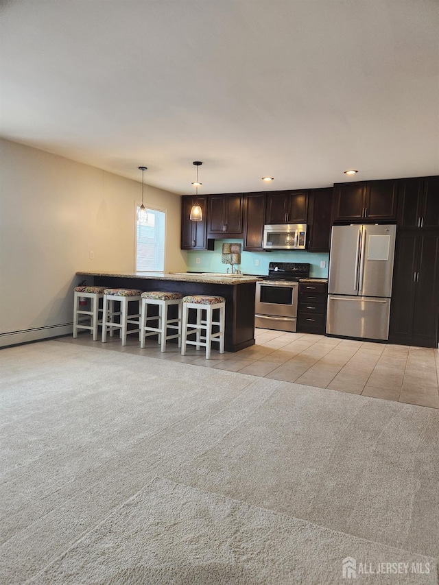 kitchen with pendant lighting, a breakfast bar area, light tile patterned floors, appliances with stainless steel finishes, and dark brown cabinets