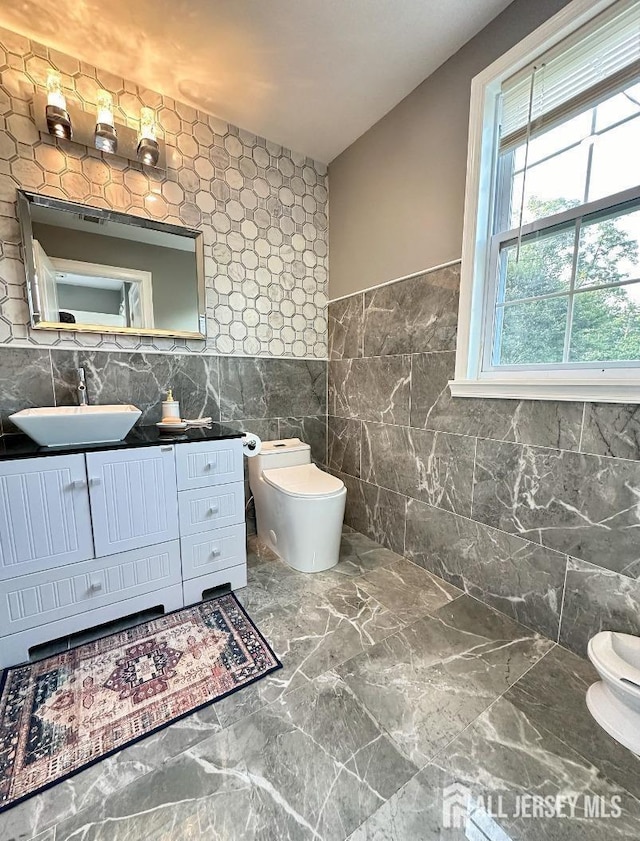 bathroom featuring vanity, toilet, tile walls, and marble finish floor